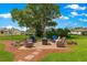 Brick patio area with comfortable wicker furniture and mature tree creating a relaxing backyard space at 9790 Se 175Th St, Summerfield, FL 34491