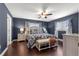Stylishly decorated bedroom features blue walls, a decorative ceiling fan, and hardwood floors at 9790 Se 175Th St, Summerfield, FL 34491