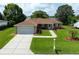 Well-maintained single-story home with a manicured lawn, large driveway, and attached two-car garage at 9790 Se 175Th St, Summerfield, FL 34491