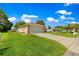 Lovely home with a well-maintained lawn and driveway, framed by lush greenery and a clear blue sky with scattered clouds at 9790 Se 175Th St, Summerfield, FL 34491
