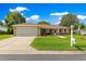 Charming single-story home with a well-manicured lawn and two-car garage, set against a backdrop of blue skies and fluffy clouds at 9790 Se 175Th St, Summerfield, FL 34491