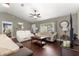 Cozy living room with hardwood floors, neutral decor, a ceiling fan, and a large window for natural light and backyard views at 9790 Se 175Th St, Summerfield, FL 34491