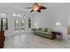 Bright living room with wood-look flooring, ceiling fan, and double doors to the outdoor living space at 1055 Avenida Sonoma, Lady Lake, FL 32159