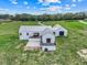 Aerial shot of a modern white farmhouse, manicured landscaping, and expansive green fields, offering scenic views at 10711 County Road 561, Clermont, FL 34711