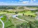 Aerial view of the property featuring the home, green pasture and wooded landscape at 10711 County Road 561, Clermont, FL 34711