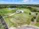 Wide aerial shot showcasing property, modern farmhouse, and natural landscape with grassy fields at 10711 County Road 561, Clermont, FL 34711