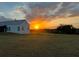 Exterior view of the property with a golden sunset, house and green pasture in view at 10711 County Road 561, Clermont, FL 34711