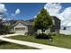 Two-story home with a large tree, neutral paint, two car garage, manicured landscaping, and a sidewalk at 1138 Calico Pointe Cir, Groveland, FL 34736