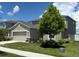 Two-story home with a large tree, neutral paint, two car garage, manicured landscaping, and a sidewalk at 1138 Calico Pointe Cir, Groveland, FL 34736