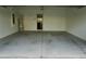 An empty two car garage, with a water heater, electric panel and a peek into the kitchen at 1138 Calico Pointe Cir, Groveland, FL 34736