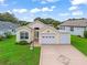 Charming home featuring well-maintained lawn, driveway with decorative detail, and two-car garage at 1142 W Boone Ct, Lady Lake, FL 32159