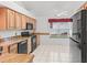 Bright kitchen with light wood cabinets, white tile floors, and black appliances at 1142 W Boone Ct, Lady Lake, FL 32159