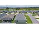 Aerial shot of residential homes, manicured lawns, trees, a pond and lush greenery; clear blue sky overhead at 1478 Erika Pl, The Villages, FL 32163
