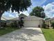 Attractive one-story home with a well-manicured lawn, mature trees, and a two-car garage at 15509 Markham Dr, Clermont, FL 34714