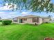 Spacious backyard features lush green grass, red shutters, and a peaceful outdoor retreat at 1948 Harston Trl, The Villages, FL 32162