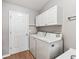 Well-lit laundry room featuring a washer, dryer, and storage cabinets for added convenience at 1948 Harston Trl, The Villages, FL 32162