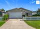 Charming single-story home featuring a well-maintained lawn, a white picket fence, and an attached two-car garage at 2311 Pine Ridge St, The Villages, FL 32162