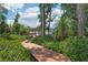 Scenic backyard with a wooden walkway leading to a gazebo by the water, surrounded by lush greenery at 2512 Baywater Rd, Tavares, FL 32778