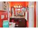 Well-lit bathroom vanity with mirror, stool, and storage in a bright, red-walled setting at 2512 Baywater Rd, Tavares, FL 32778