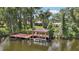 Waterfront property with a private wooden dock and covered boathouse on a lushly vegetated canal with home in the background at 2512 Baywater Rd, Tavares, FL 32778