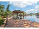 Wooden dock and covered boathouse overlooking the canal on a sunny day, with lush trees surrounding the property at 2512 Baywater Rd, Tavares, FL 32778