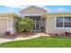 Close-up view of the front entrance with a well-kept lawn and a decorative palm tree at 27328 Pine Straw Rd, Leesburg, FL 34748