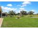 Spacious front yard featuring green lawn and tropical landscaping at 27328 Pine Straw Rd, Leesburg, FL 34748