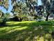 Picturesque backyard with mature trees, a sprawling lawn, and a glimpse of the home's charming architecture at 32511 Purdum Ave, Leesburg, FL 34788