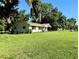 Sprawling front yard and a charming single-story home with an inviting porch nestled beneath mature trees at 32511 Purdum Ave, Leesburg, FL 34788