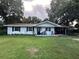 Charming single-story home with a well-manicured lawn, front porch, and mature trees at 32511 Purdum Ave, Leesburg, FL 34788