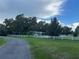 Home featuring a white fence and beautiful trees in a serene outdoor setting at 32511 Purdum Ave, Leesburg, FL 34788