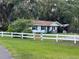 Charming white house with black shutters and a white fence in a lush, green setting at 32511 Purdum Ave, Leesburg, FL 34788