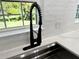 Close-up of modern kitchen sink, faucet, and white quartz countertop and backsplash, illuminated by natural light at 32511 Purdum Ave, Leesburg, FL 34788