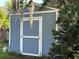 Backyard view of a blue shed with white trim and a propane tank to the side at 32511 Purdum Ave, Leesburg, FL 34788