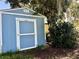 Blue shed with white trim surrounded by lush greenery and moss-covered trees at 32511 Purdum Ave, Leesburg, FL 34788