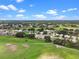 Aerial view of a home in a beautiful neighborhood near golf course under a sunny sky with white puffy clouds at 4909 Kelso St, Leesburg, FL 34748