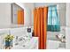 Bathroom featuring shower with orange curtain, sink, toilet, and large mirror at 501 Washington Ave, Eustis, FL 32726