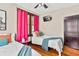 Bright bedroom featuring two twin beds, wood floors, and hot pink curtains at 501 Washington Ave, Eustis, FL 32726