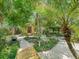 Backyard with lush landscaping, wooden pathway, small storage building, and seating areas at 504 Gilliam St, Wildwood, FL 34785