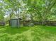 Backyard with shed, raised garden beds, a lush lawn and mature trees at 504 Gilliam St, Wildwood, FL 34785
