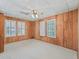 Bedroom with carpet flooring, wood paneling, ceiling fan, and abundant natural light from multiple windows at 504 Gilliam St, Wildwood, FL 34785