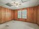 Bright bedroom with wood paneled walls, ceiling fan, and natural light from the shuttered window at 504 Gilliam St, Wildwood, FL 34785