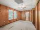 Spacious bedroom with wood paneling, a ceiling fan, a large window, and an ensuite bathroom at 504 Gilliam St, Wildwood, FL 34785
