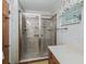 Bathroom showcasing a glass-enclosed walk-in shower with tiled walls, along with a vanity area and a bright window at 504 Gilliam St, Wildwood, FL 34785