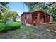 Rear view of a cozy red home with mature trees and a shed at 54544 Buckhorn Rd, Astor, FL 32102