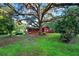 Quaint red home nestled beneath a large, moss-draped tree providing ample shade at 54544 Buckhorn Rd, Astor, FL 32102