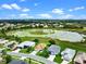 Aerial view showcases the home, verdant lawns, landscaping, and a serene pond, enhancing the property's appeal at 5715 Illumination Ln, Leesburg, FL 34748