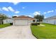 Lovely single-story home featuring a manicured lawn, two-car garage, and picturesque landscaping at 5715 Illumination Ln, Leesburg, FL 34748