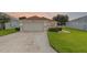 Inviting single-story home with a paved driveway, two-car garage, and beautifully maintained lawn at 5715 Illumination Ln, Leesburg, FL 34748