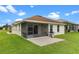 Rear exterior view showcasing a cozy lanai, open patio, grill, and lush yard at 5715 Illumination Ln, Leesburg, FL 34748